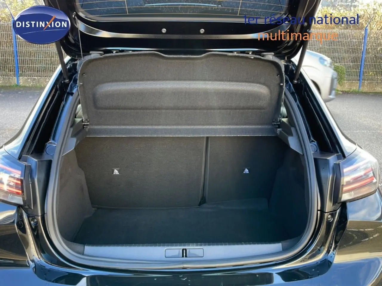 Coffre ouvert vu de l'arrière d'une Peugeot 208 noire 2025, montrant un espace de chargement vide et propre.