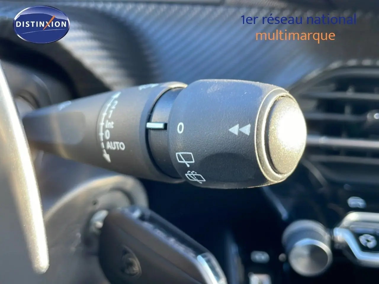 Gros plan sur la commande d’essuie-glace à gauche du volant dans l’habitacle noir d’une Peugeot 208 1.2 Hybrid 2025.