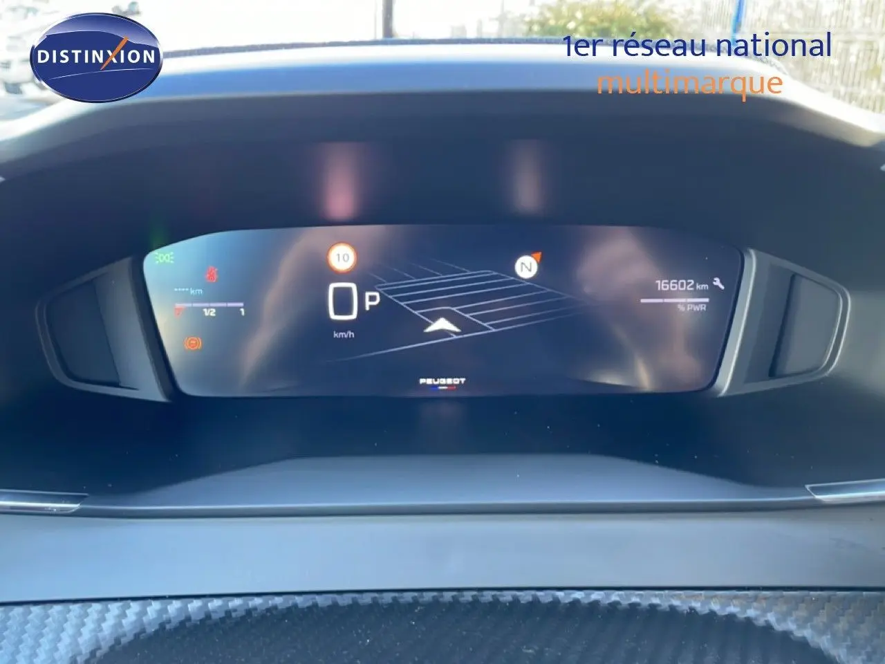 Vue rapprochée du tableau de bord numérique de la Peugeot 208 noire, affichant la vitesse et la navigation.