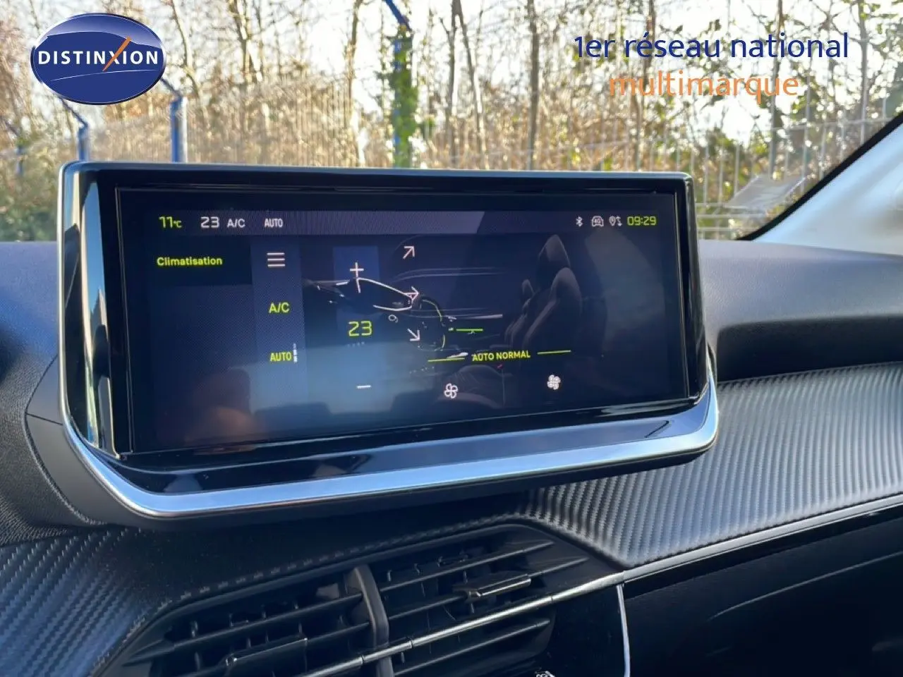 Vue rapprochée de l'écran tactile central affichant la climatisation dans l'habitacle gris noir d'une Peugeot 208 noire 2025.