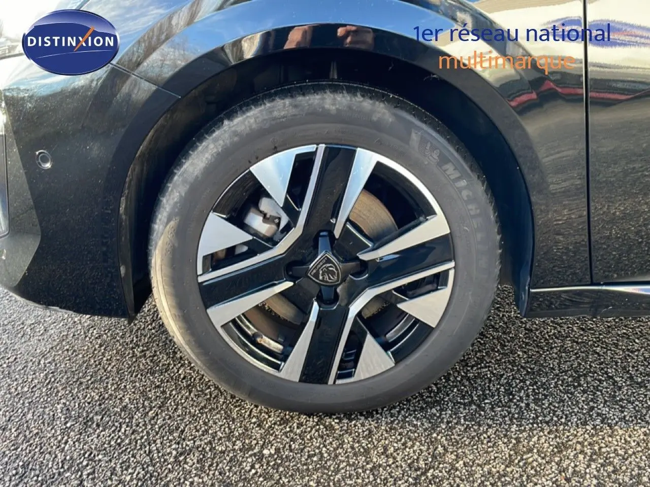 Gros plan sur la roue avant gauche noire d’une Peugeot 208 1.2 Hybrid 110ch avec jante alliage bicolore.