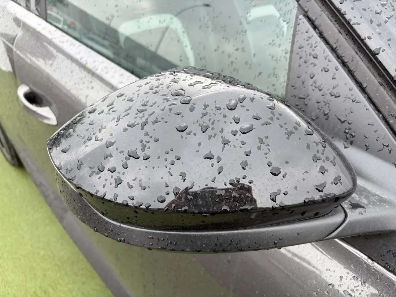 Rétroviseur extérieur droit noir brillant d'un Citroën C5 Aircross Platinium avec gouttes de pluie visible de près.