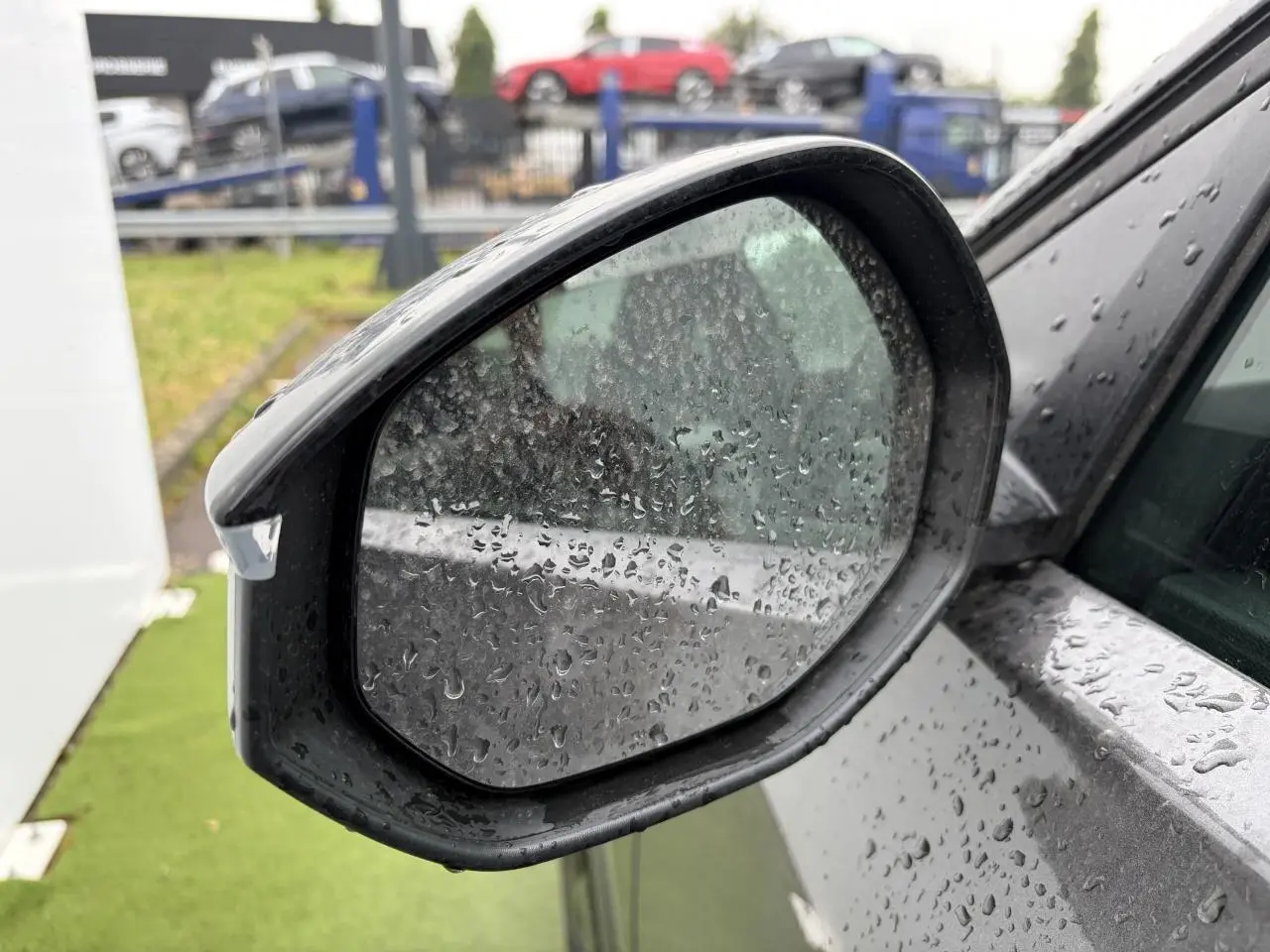 Rétroviseur extérieur côté gauche d'une Citroën C5 Aircross platinium avec toit noir, vue rapprochée sous la pluie.