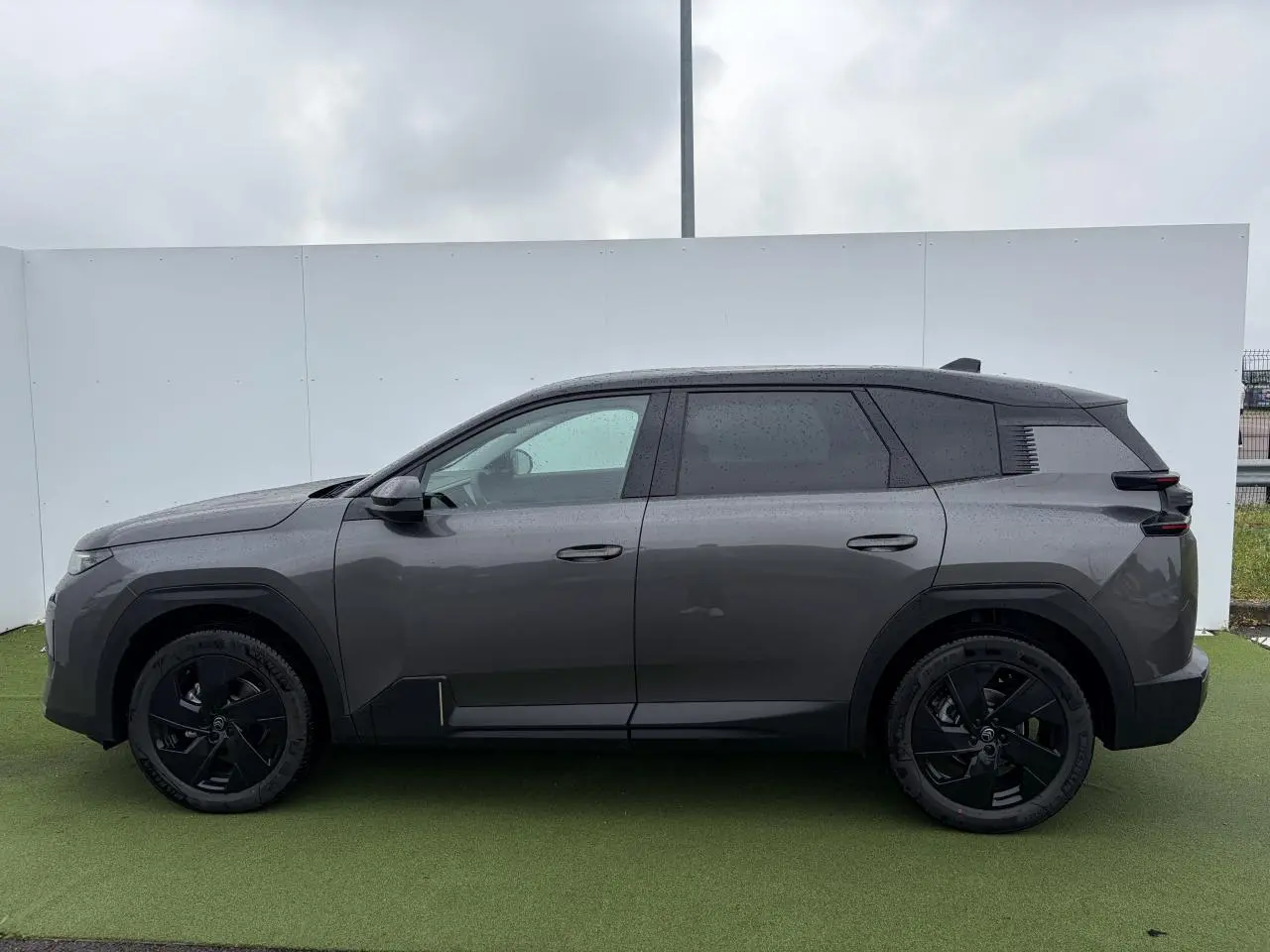 Vue de profil côté gauche d'un Citroën C5 Aircross 2026 gris platinium avec toit noir et jantes alliage noires.
