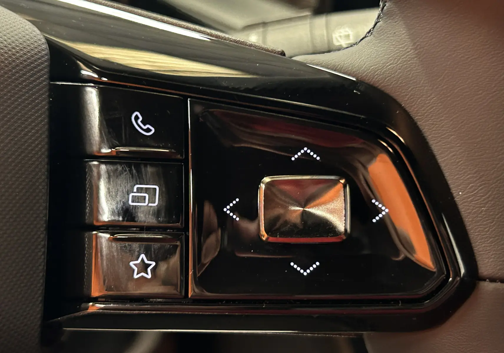 Gros plan sur les commandes au volant noir brillant du MG3 1.5 Hybrid+ 195 Luxury, boutons rétroéclairés blancs.