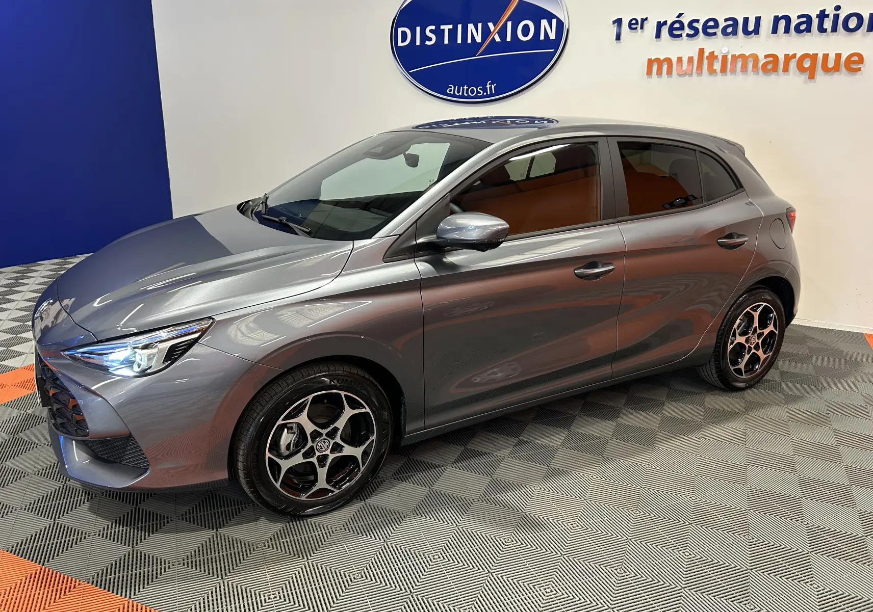 Vue 3/4 avant droite de la MG3 1.5 Hybrid+ 195 Luxury gris Hampstead avec jantes noires et intérieur marron visible.