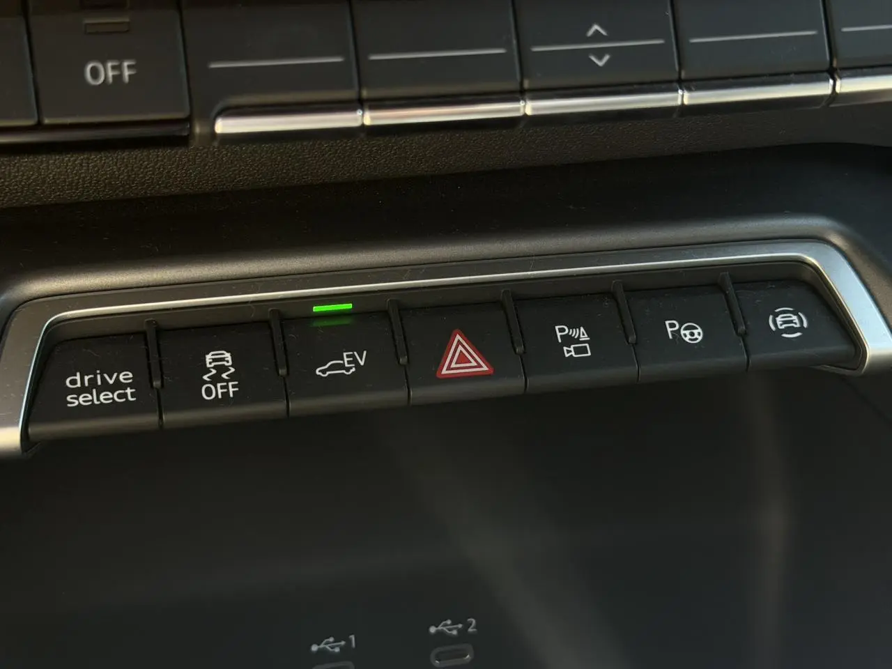 Gros plan sur les boutons de commande du tableau de bord de l'Audi A3 Sportback bleu Navarre, avec témoin EV vert allumé.