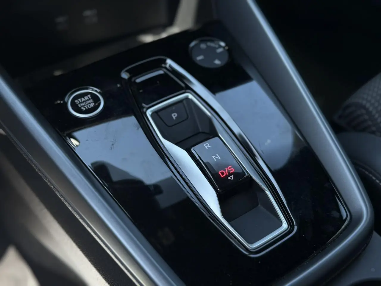 Gros plan sur la console centrale noire brillante avec sélecteur de boîte auto et bouton Start/Stop de l'Audi A3 Sportback.