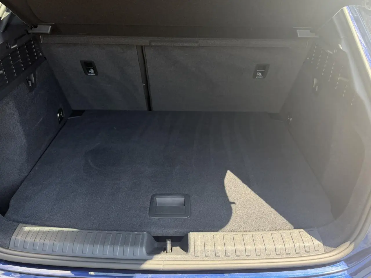 Coffre ouvert vu de face d'une Audi A3 Sportback Bleu Navarre avec intérieur de coffre noir et tapis plat.