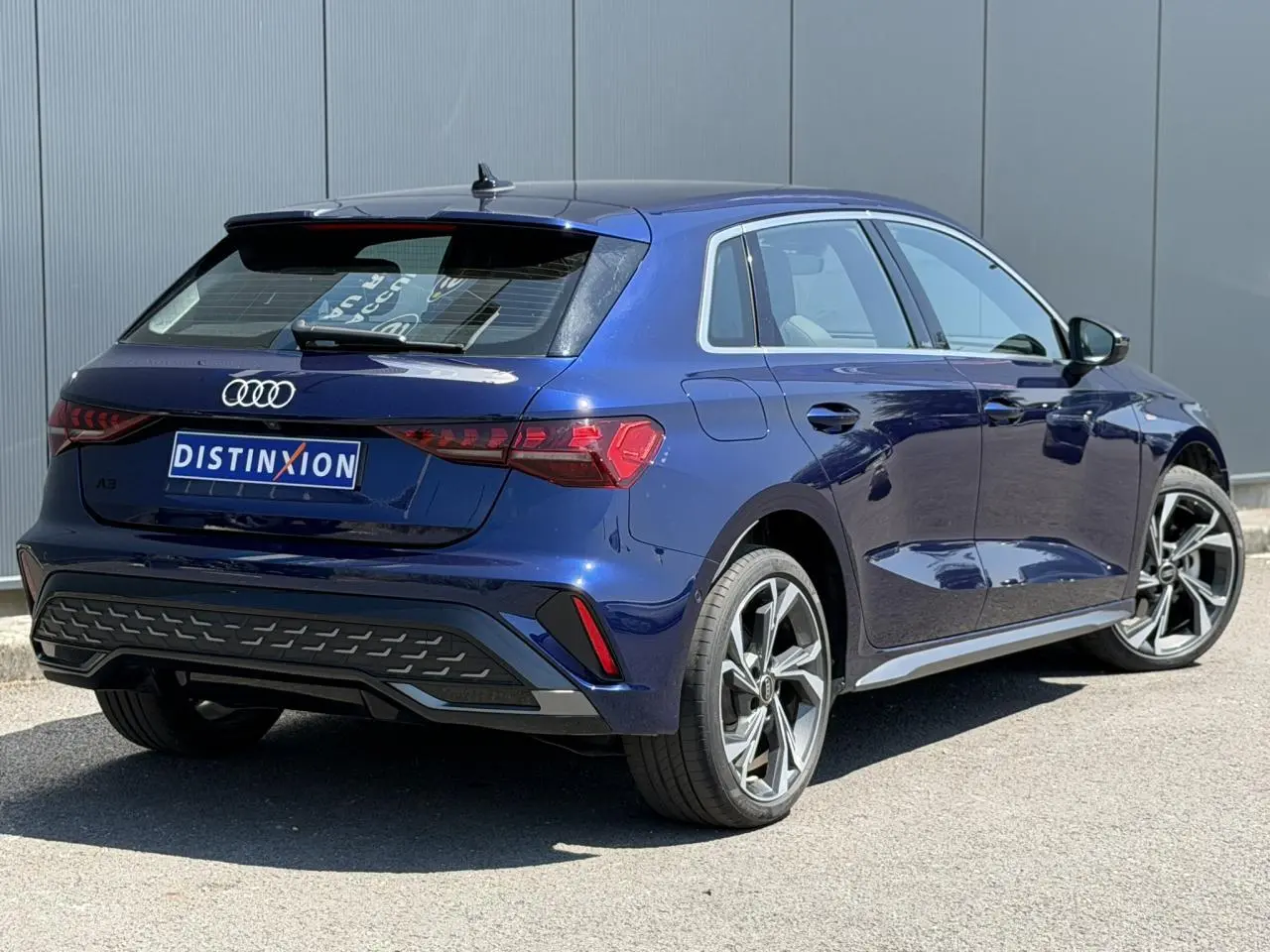 Vue 3/4 arrière droite d'une Audi A3 Sportback 2025 bleu Navarre avec jantes alliage 18 pouces et feux LED dynamiques.