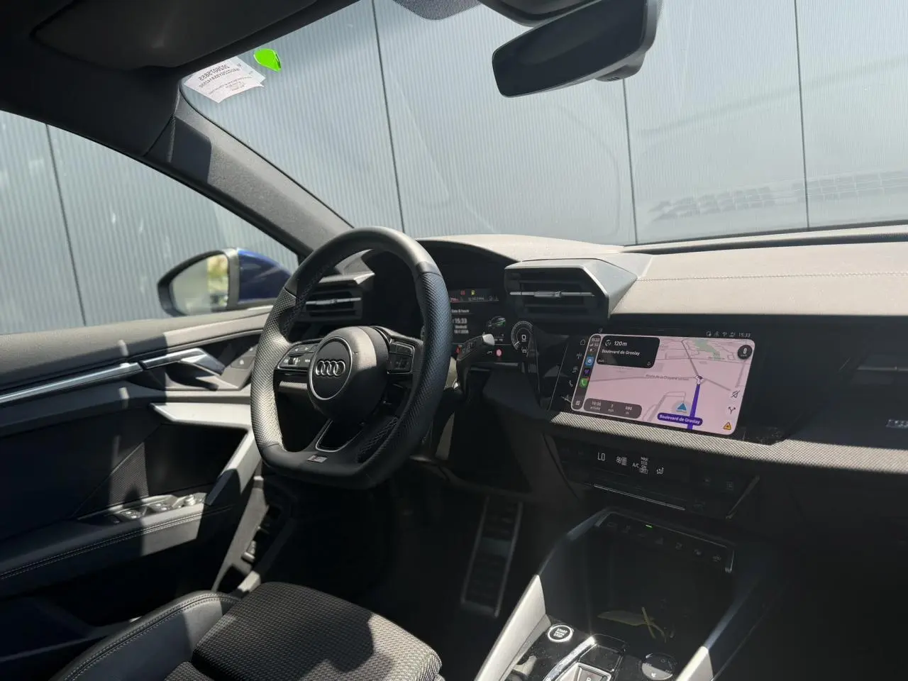 Vue intérieure côté conducteur de l'Audi A3 Sportback bleu Navarre, avec tableau de bord numérique et écran central tactile.