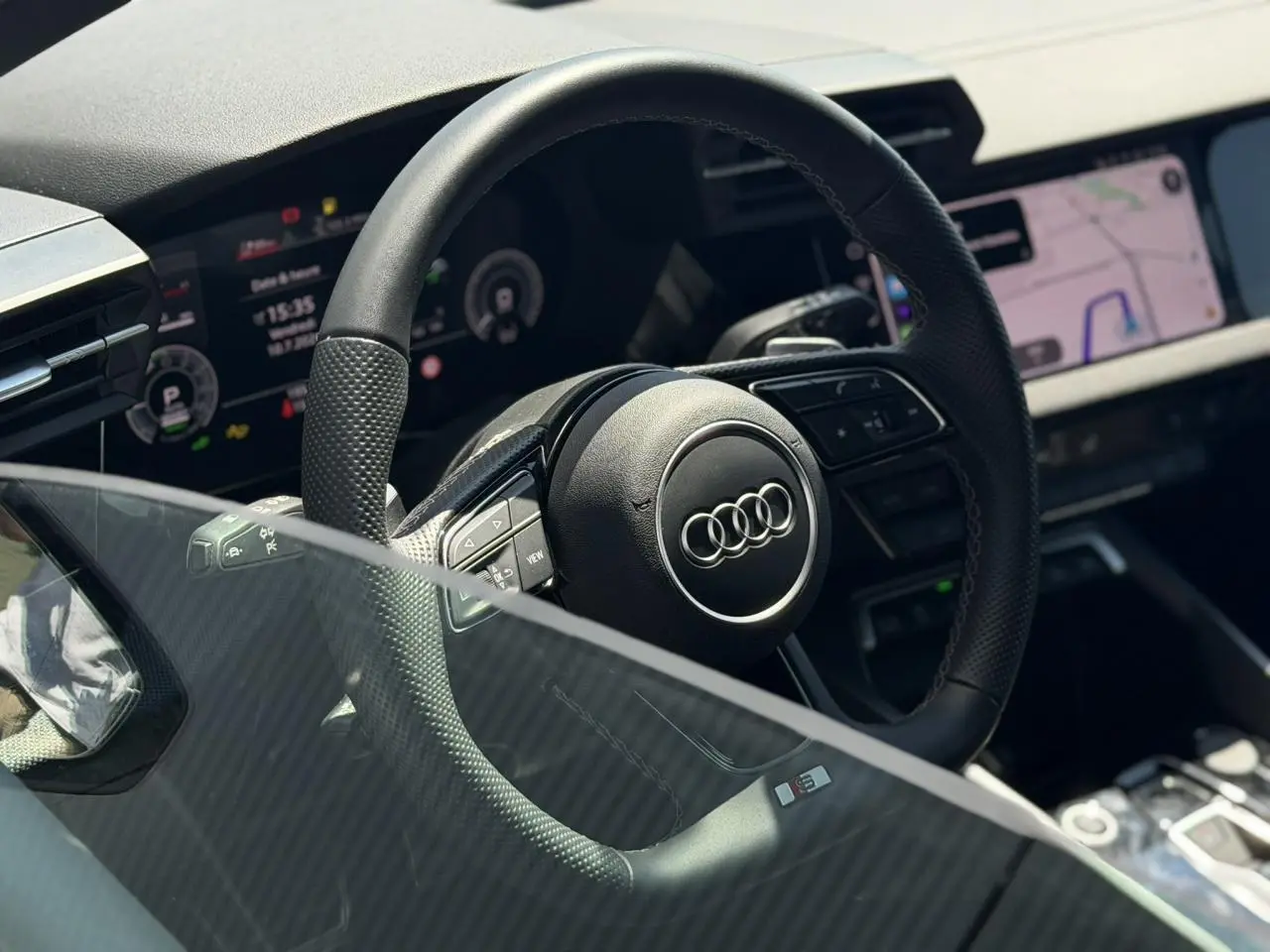 Vue rapprochée du volant cuir perforé avec logo Audi et tableau de bord numérique de l’A3 Sportback 2025.