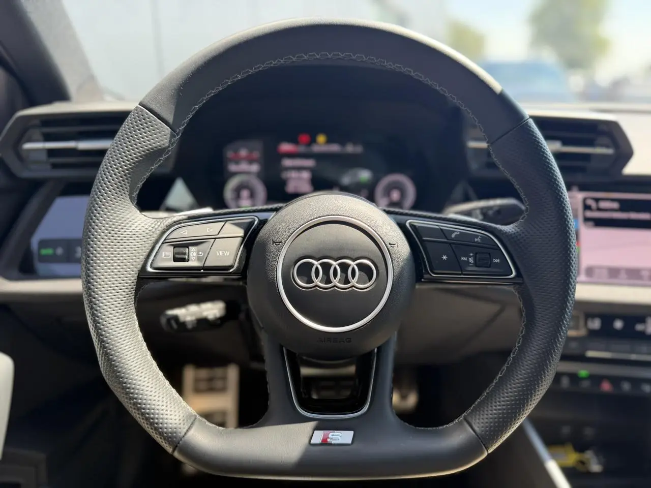Volant sport Audi S avec commandes multifonctions en cuir perforé, vue frontale de l’habitacle de l’Audi A3 Sportback 2025.