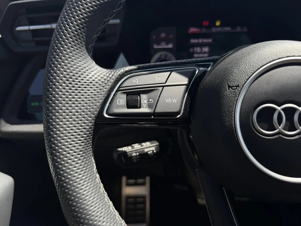 Gros plan sur le volant cuir perforé de l'Audi A3 Sportback 2025 avec commandes multifonctions côté gauche.