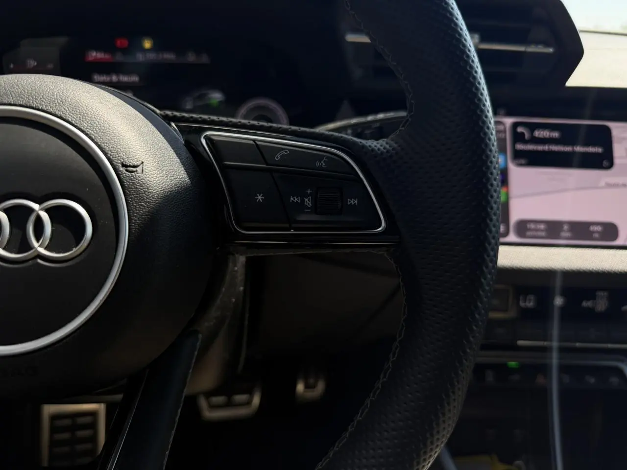 Gros plan sur le volant cuir perforé de l'Audi A3 Sportback 2025 avec commandes multifonctions et tableau de bord numérique.