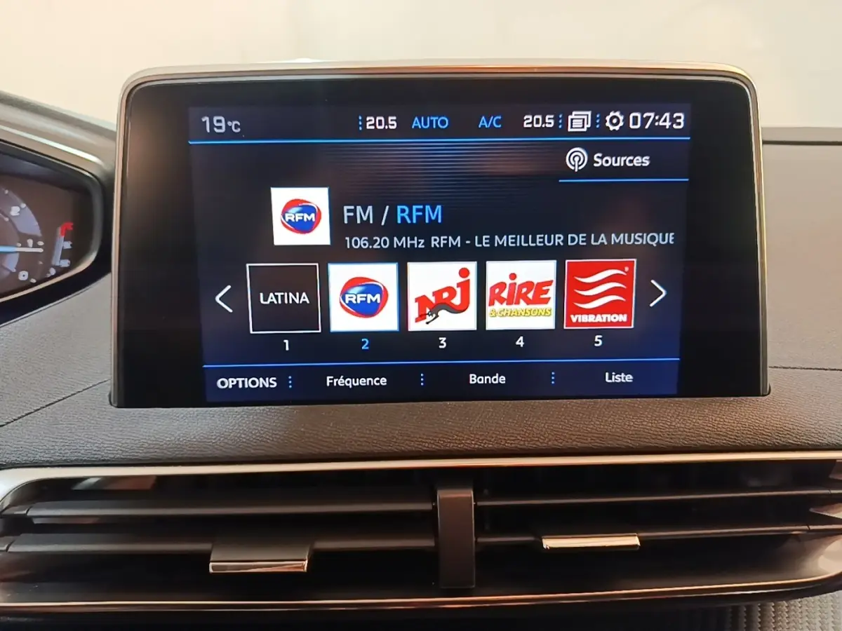 Écran tactile central du tableau de bord du Peugeot 5008 noir, affichant les stations radio FM avec interface moderne.