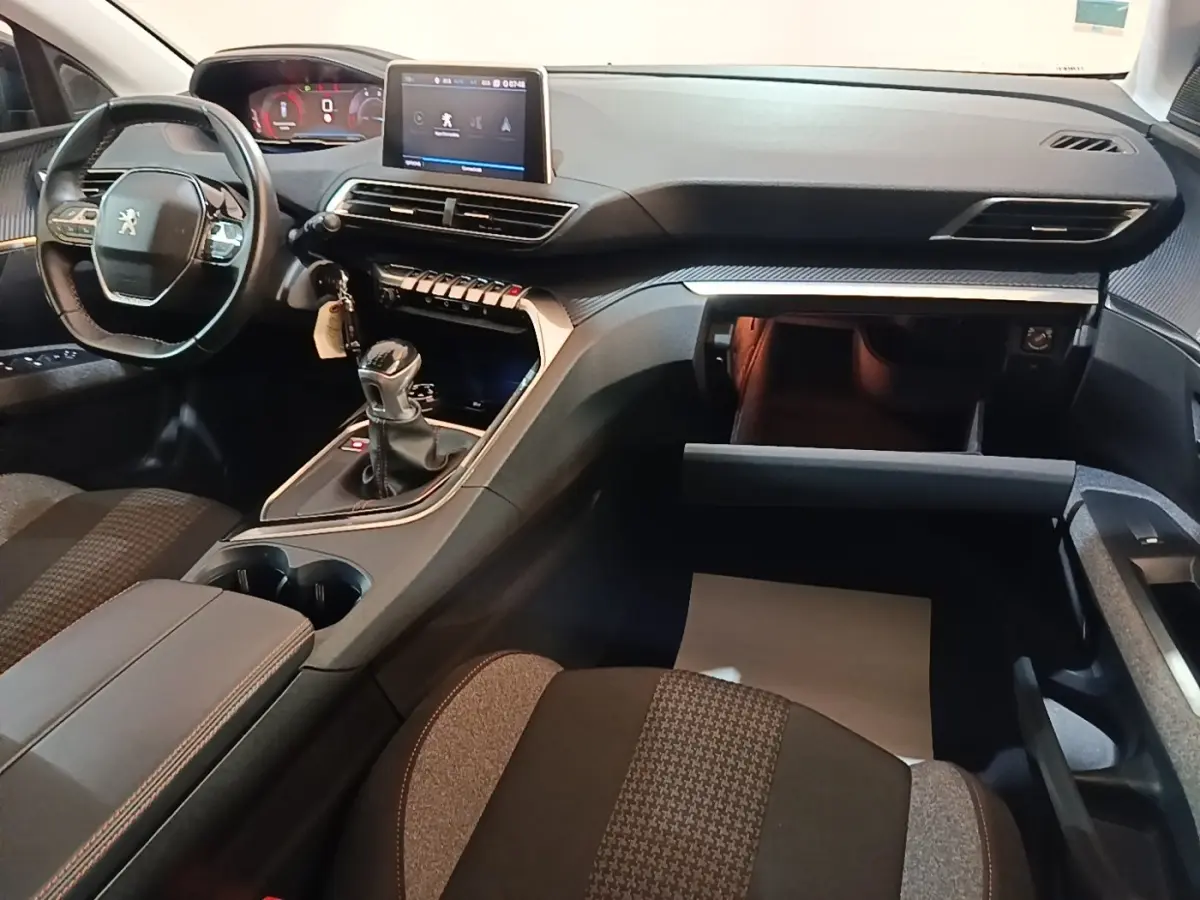 Intérieur Peugeot 5008 2018 noir, vue côté passager montrant tableau de bord, écran tactile et boîte manuelle ouverte.
