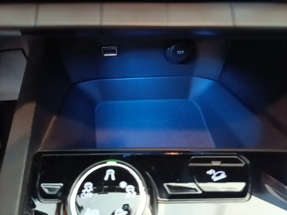 Gros plan sur la console centrale noire du Peugeot 5008, avec molette de sélection des modes de conduite et prise 12V visible.