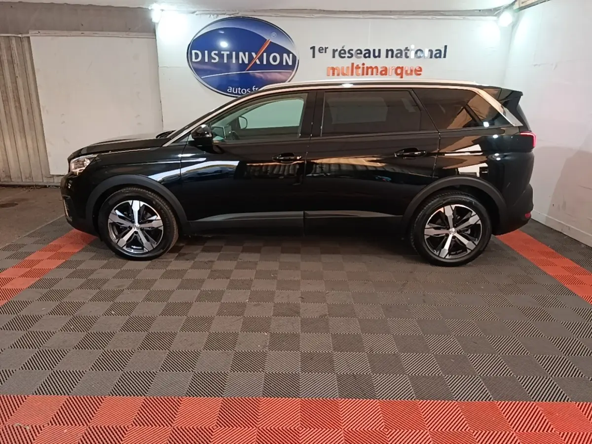 Peugeot 5008 noir vue de profil côté gauche, avec jantes alliage et vitres teintées dans un showroom.