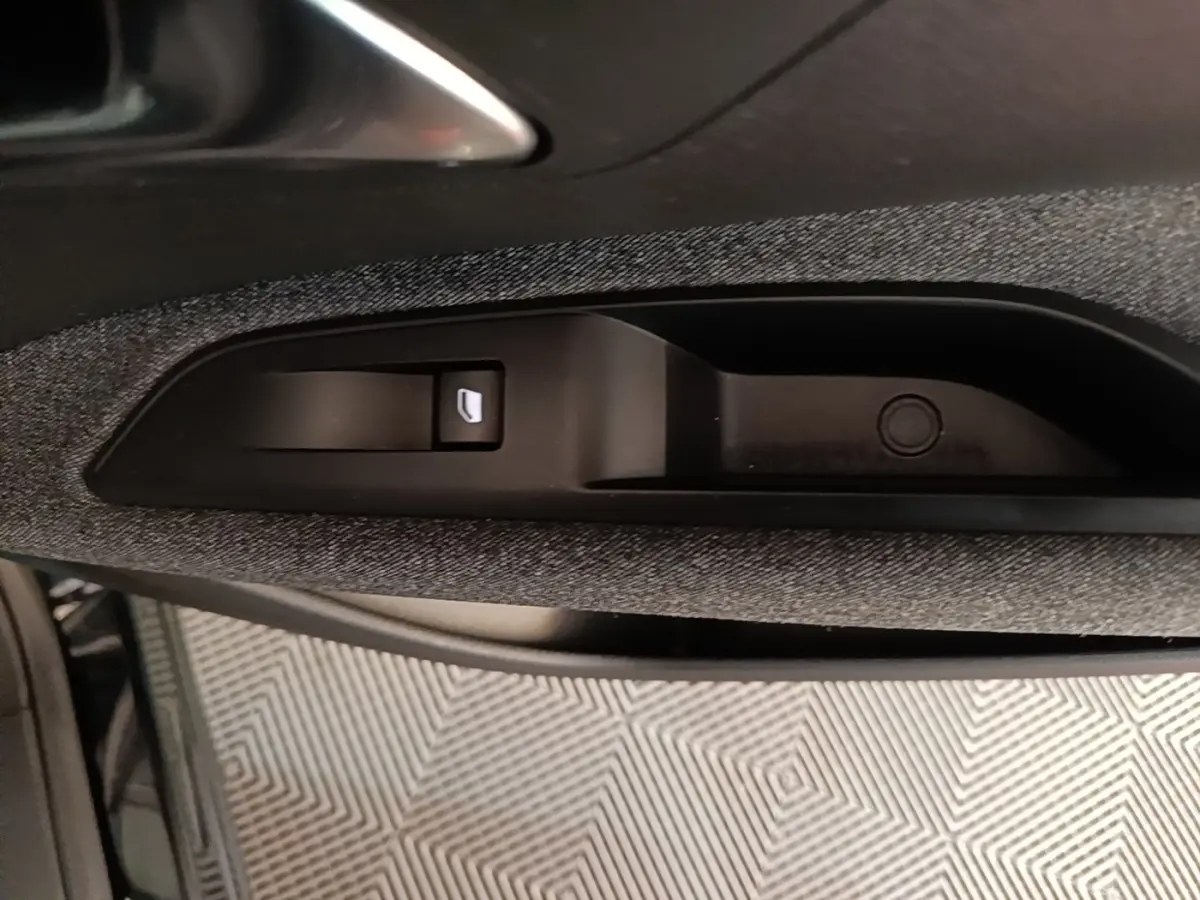 Gros plan sur la commande de lève-vitre électrique intégrée dans la porte côté conducteur du Peugeot 5008 noir.