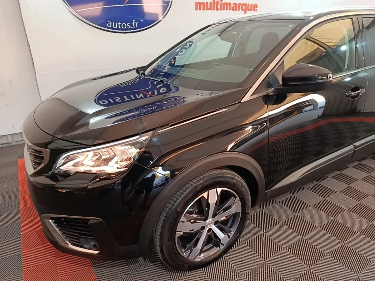 Vue 3/4 avant droit du Peugeot 5008 noir avec phares allumés et jantes alliage modernes.