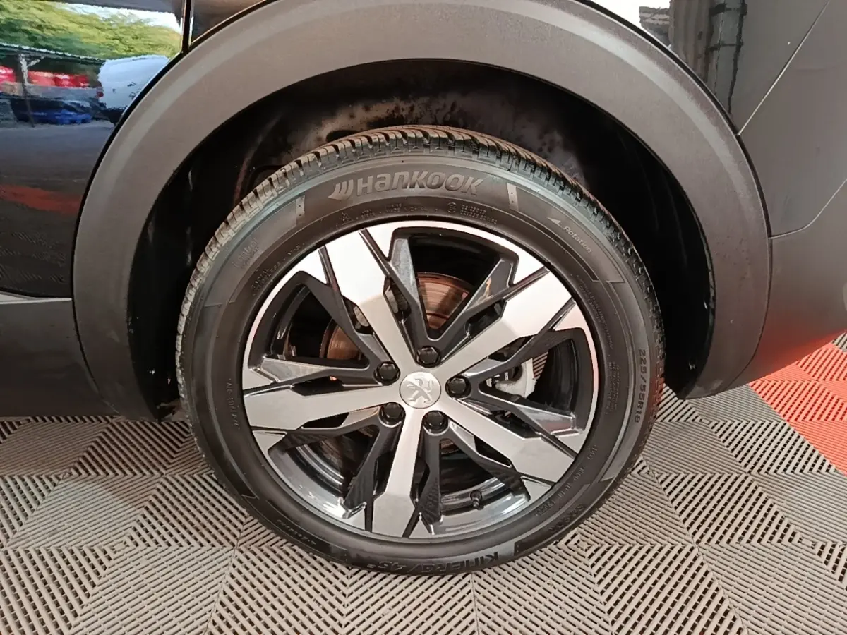 Gros plan sur la roue avant droite noire du Peugeot 5008 avec jante alliage bicolore et pneu Hankook.