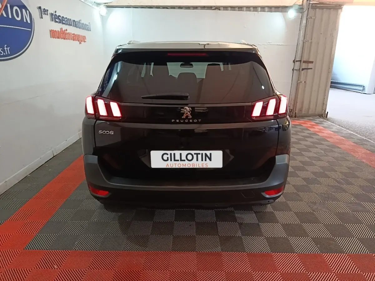 Vue arrière d’un Peugeot 5008 noir avec feux LED caractéristiques allumés dans un garage.