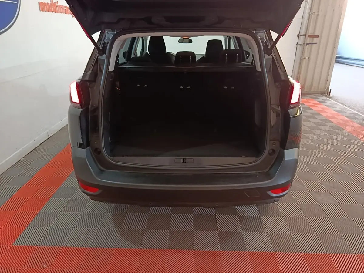 Vue arrière d'un Peugeot 5008 noir 2018 avec coffre ouvert et feux arrière allumés dans un garage.