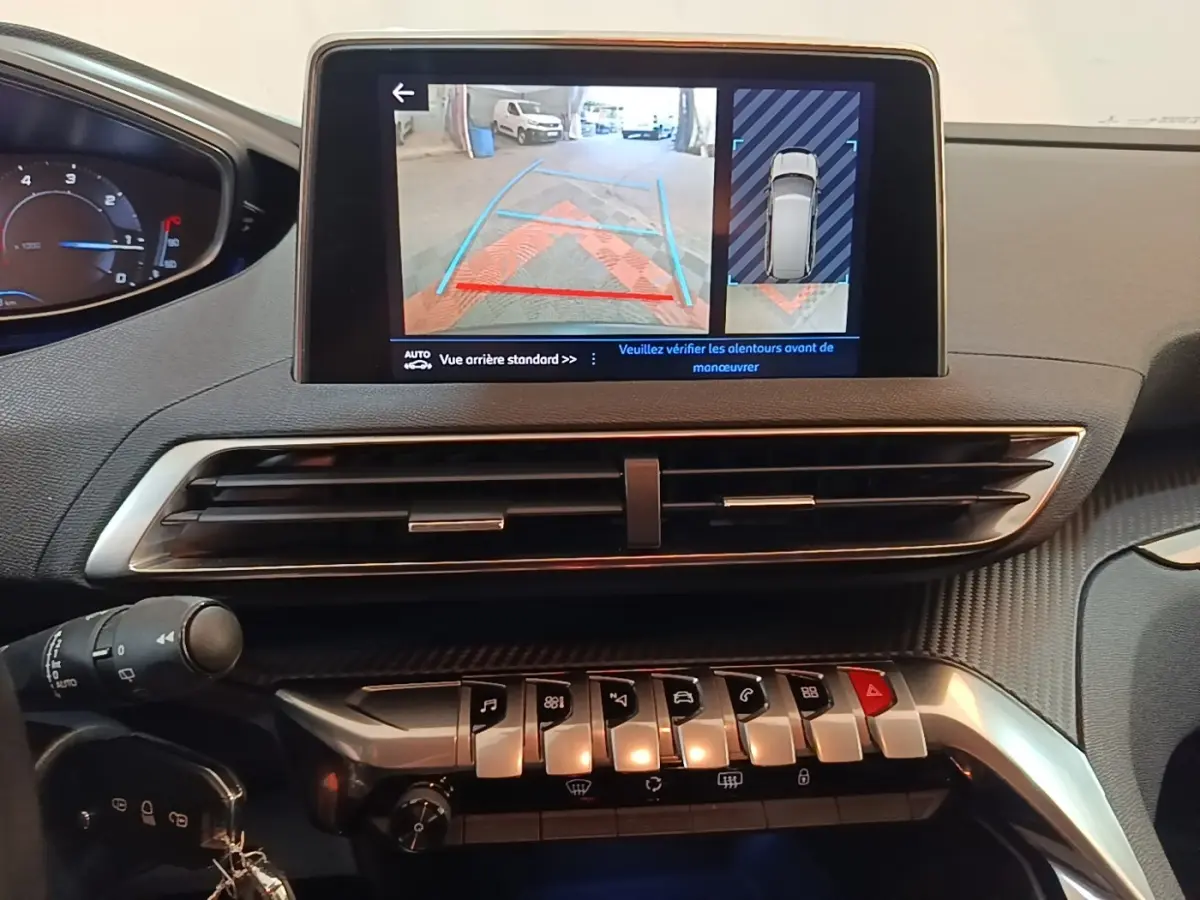 Vue intérieure du tableau de bord du Peugeot 5008 noir, écran tactile affichant la caméra de recul avec guidage.