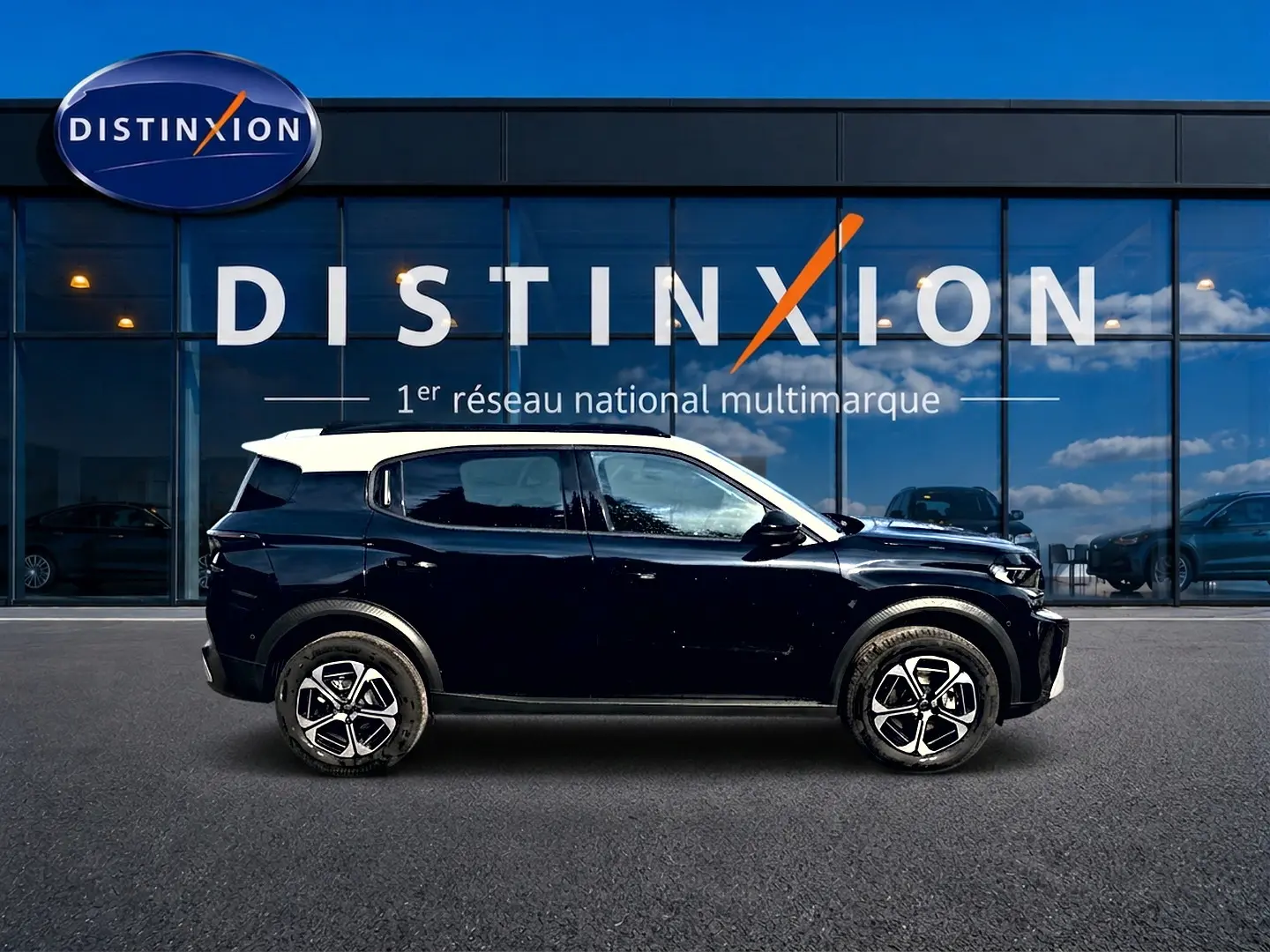 Vue latérale droite d’un Citroën C3 Aircross noir avec toit blanc et jantes alu devant une vitrine Distinxion.