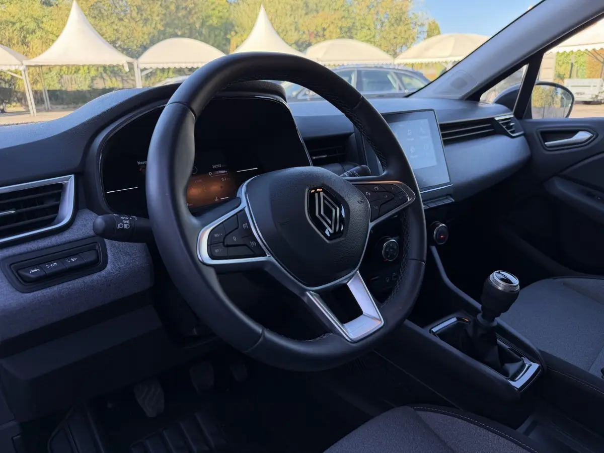 Intérieur de la Renault Clio Evolution TCe 90 2024, vue côté conducteur sur volant cuir et écran tactile central.