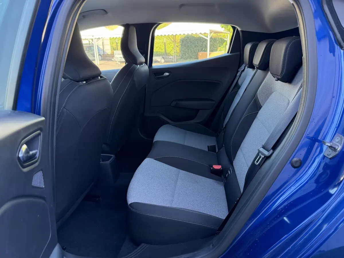 Vue intérieure côté droit sur la banquette arrière gris clair et noir d'une Renault Clio bleu 2024 avec porte ouverte.