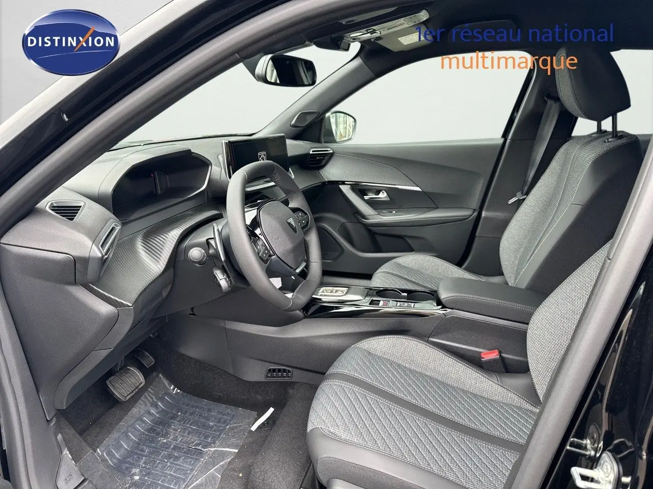 Intérieur avant du Peugeot 2008 noir métal 2025, sièges tissu gris, tableau de bord moderne et volant compact.
