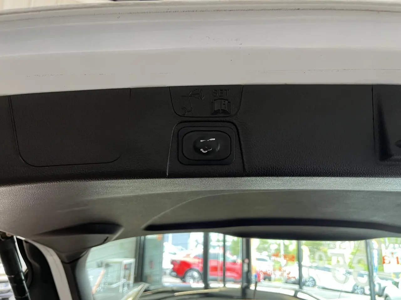 Gros plan sur la commande d'ouverture du hayon intérieur d'une Ford C-MAX blanche, vue depuis le coffre.