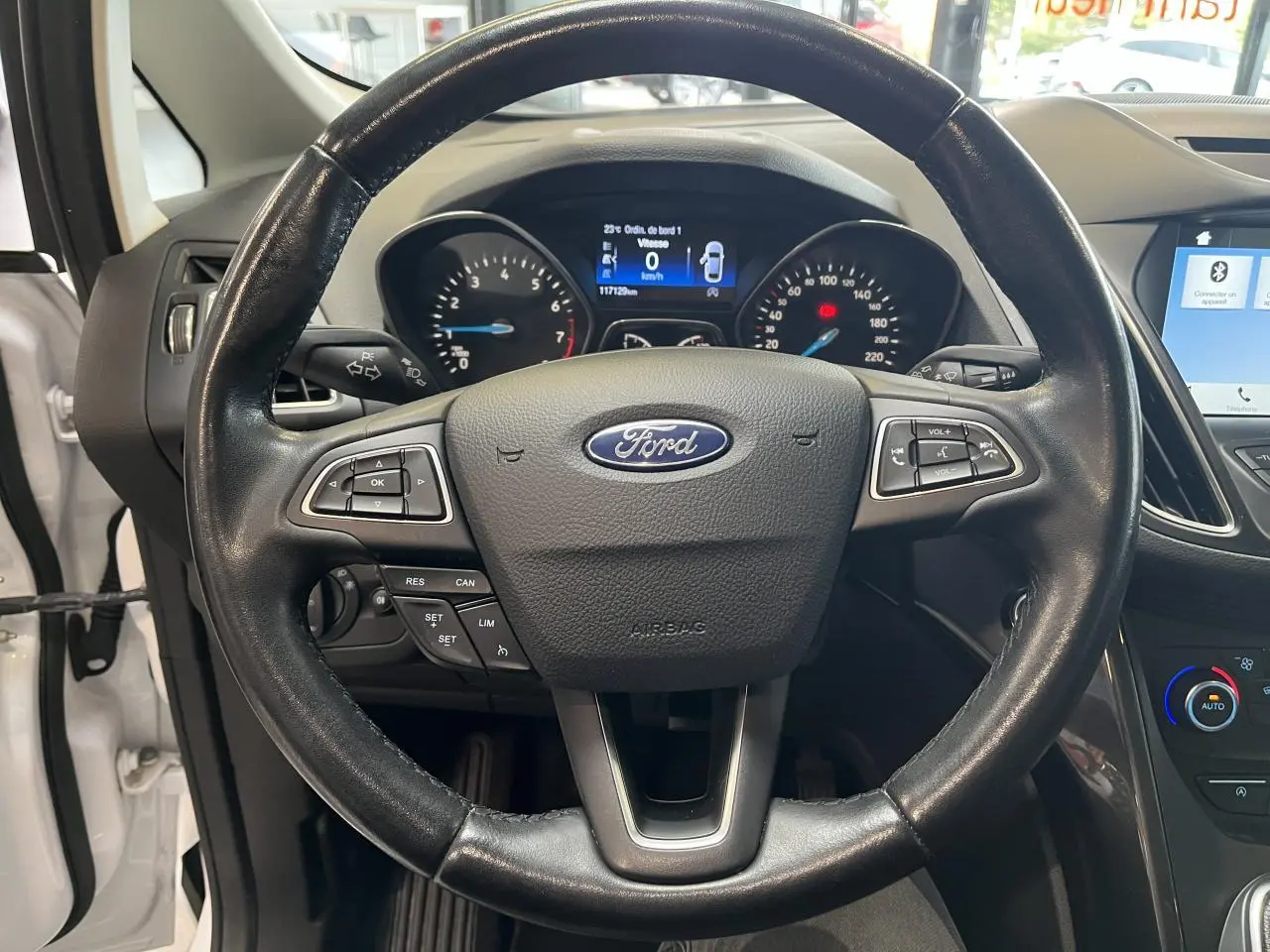 Vue rapprochée du volant en cuir noir avec logo Ford, tableau de bord et écran tactile du Ford C-MAX blanc 2018.