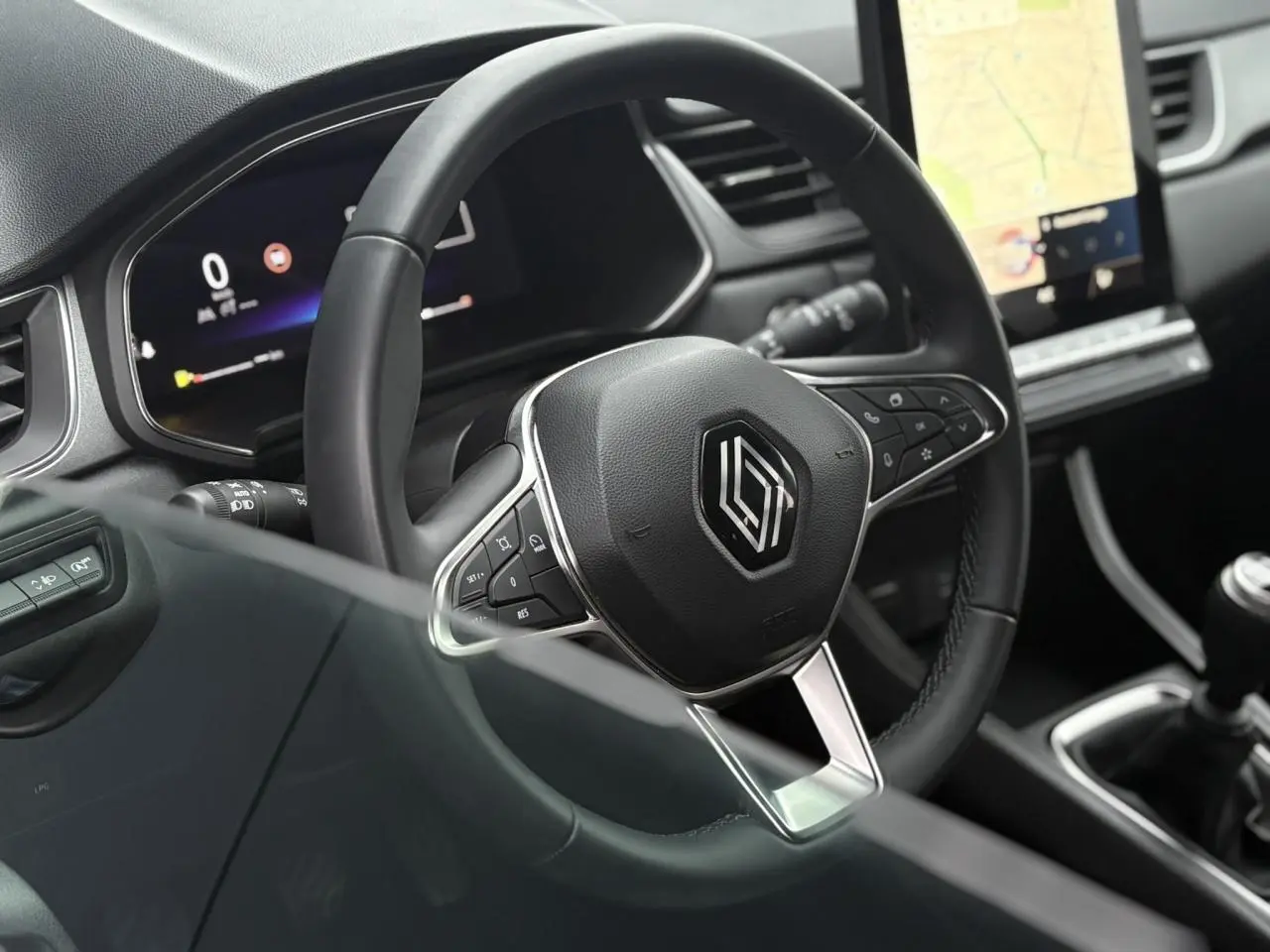 Vue rapprochée du volant noir et du tableau de bord numérique du Renault Captur 2025, avec écran tactile et levier de vitesse manuel.