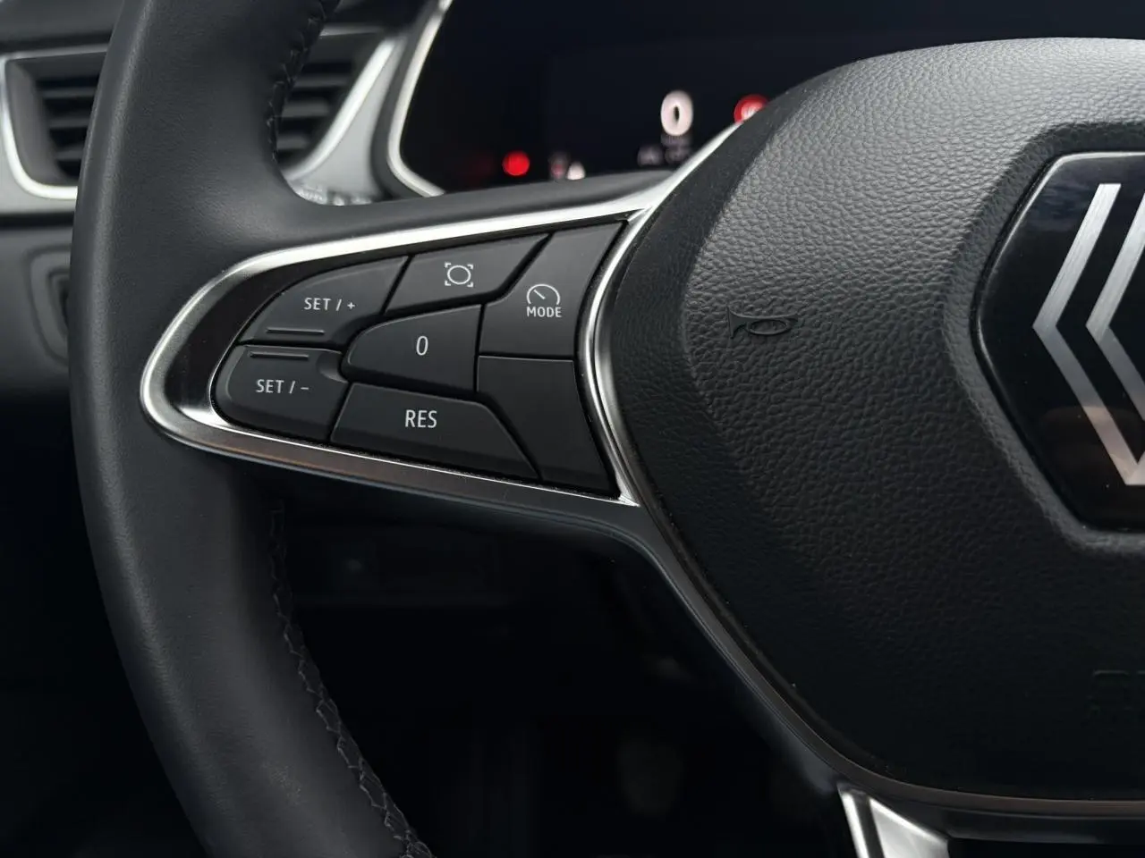 Gros plan sur le volant noir du Renault Captur 2025, mettant en valeur les commandes de régulateur de vitesse côté gauche.
