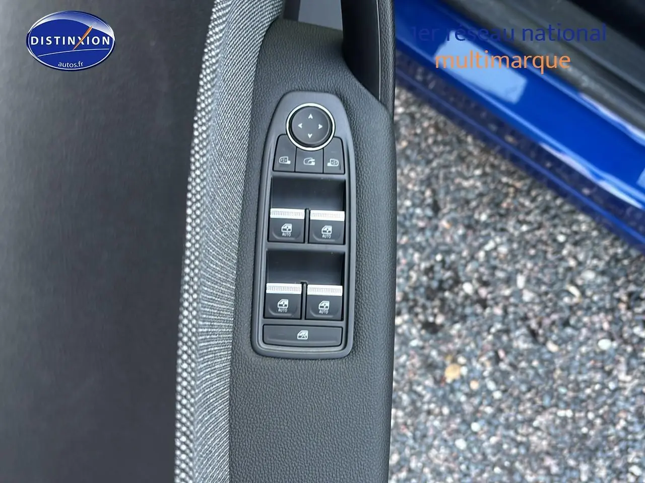 Détail des commandes des vitres électriques sur la porte avant gauche d'un Renault Captur bleu iron t/noir.