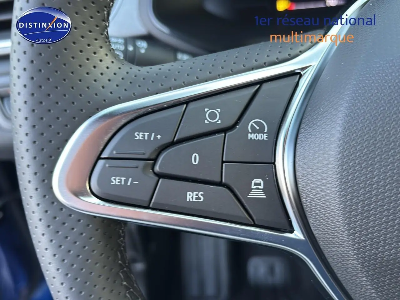 Gros plan sur les commandes multifonctions au volant perforé d’un Renault Captur bleu iron t/noir 2026.