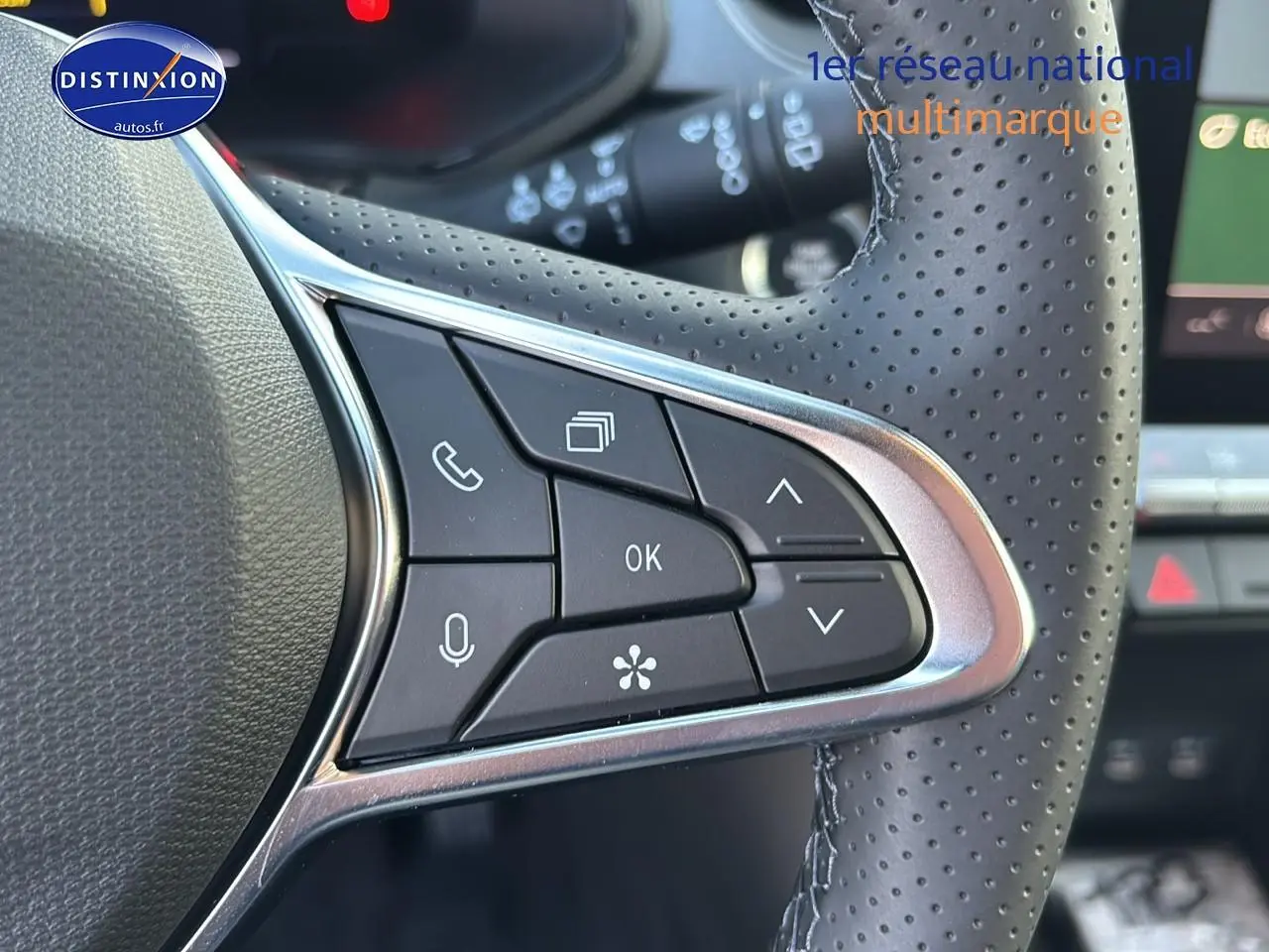 Gros plan sur les commandes multifonctions du volant en cuir perforé du Renault Captur bleu iron t/noir.