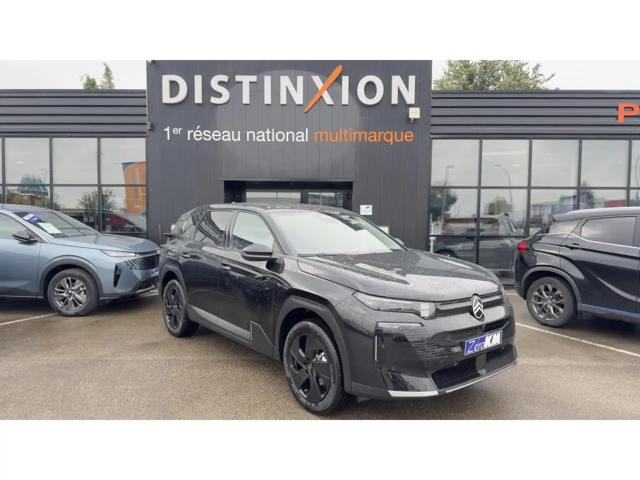 Vue 3/4 avant d'un Citroën C5 Aircross noir métal avec toit panoramique, jantes noires et calandre distinctive.