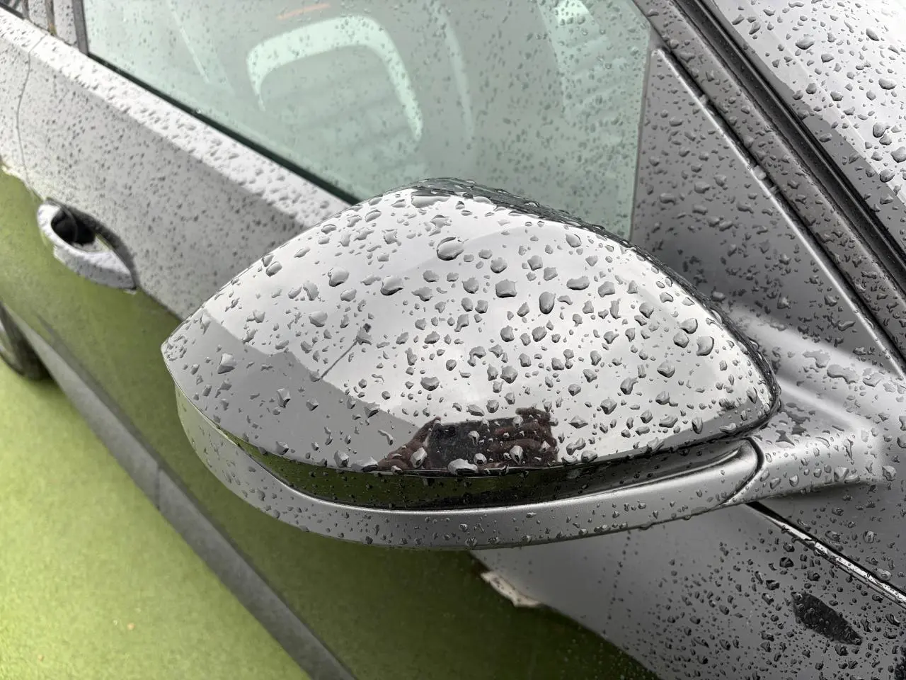 Rétroviseur droit noir métallisé de Citroën C5 Aircross 2026 avec gouttes de pluie sur la carrosserie noire.