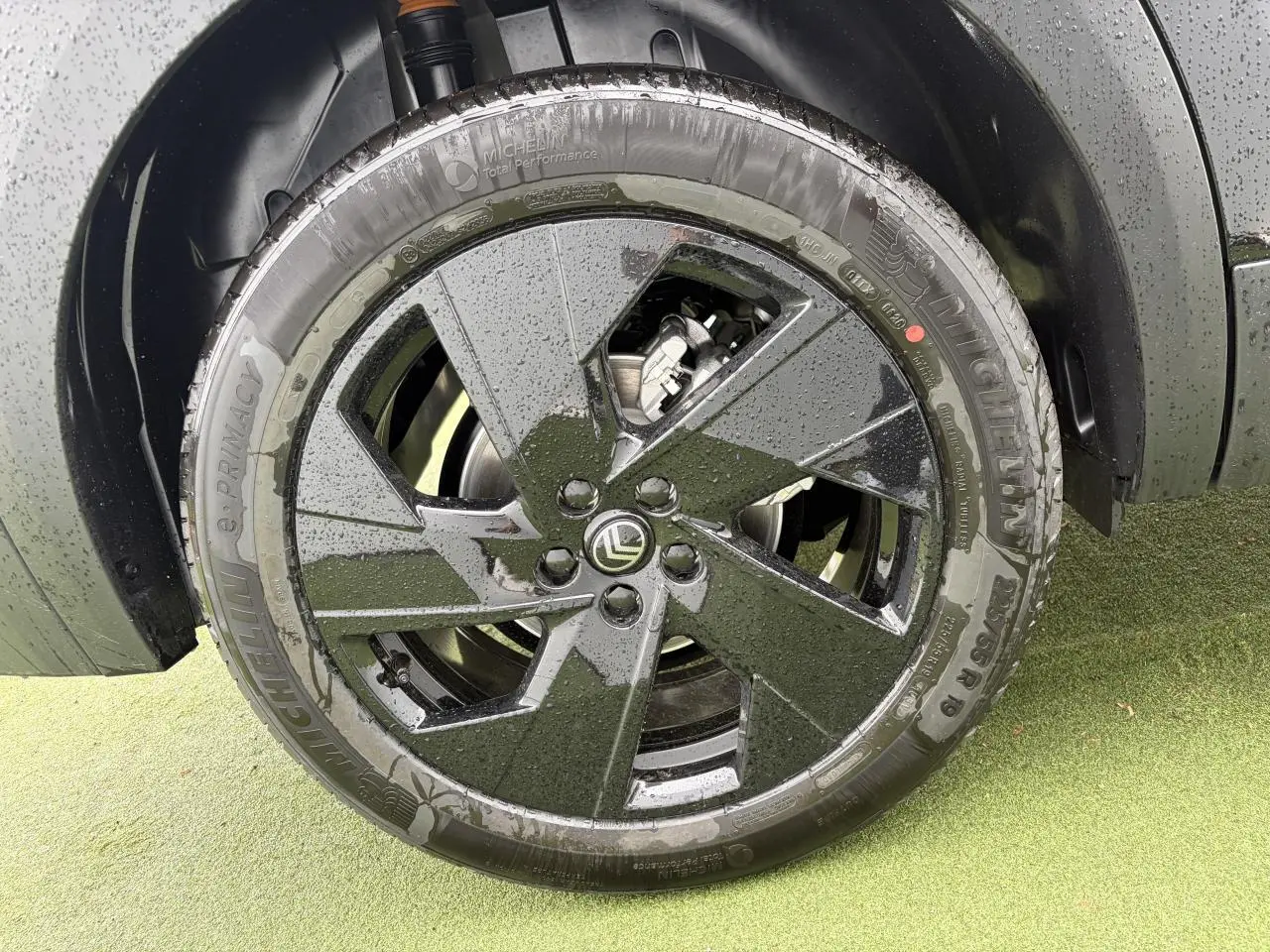 Gros plan sur la jante alliage noire 19'' Zircone d'un Citroën C5 Aircross noir métal, avec pneus Michelin mouillés.