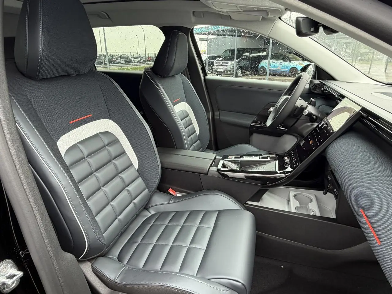 Vue intérieure côté conducteur du Citroën C5 Aircross noir métal, sièges bi-matière avec surpiqûres blanches et détails rouges.