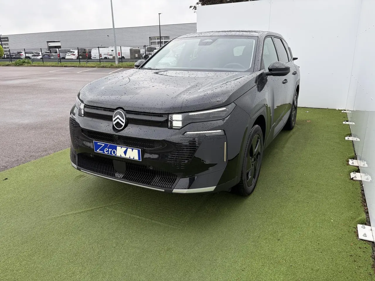 Citroën C5 Aircross noir métal en 3/4 avant droit, avec toit panoramique et plaques Zero KM visibles.