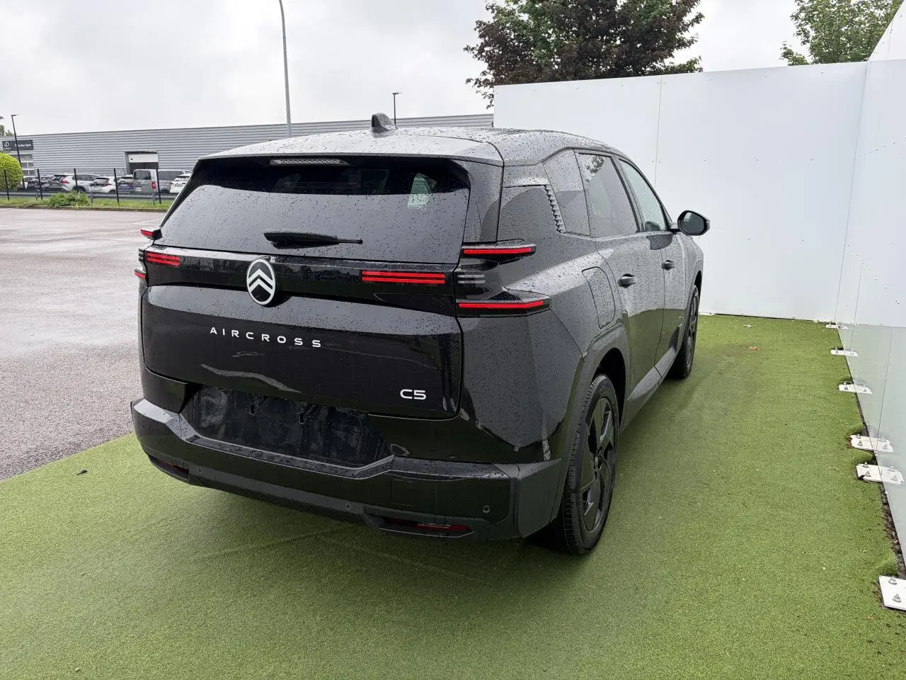 Vue 3/4 arrière droite d'un Citroën C5 Aircross noir métal avec feux arrière LED fins et toit panoramique visible.