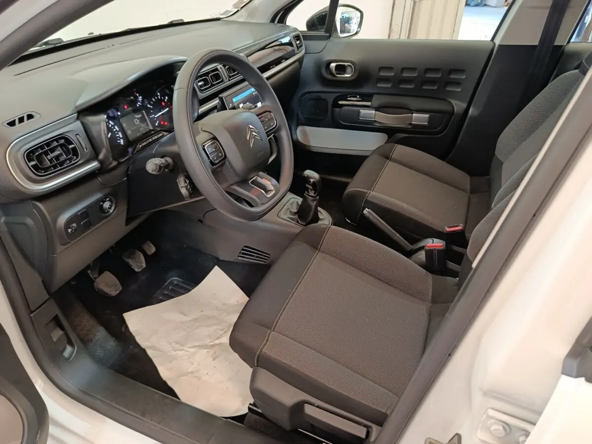 Vue intérieure côté conducteur de la Citroën C3 blanche 2020, volant multifonctions et sièges tissu noirs.