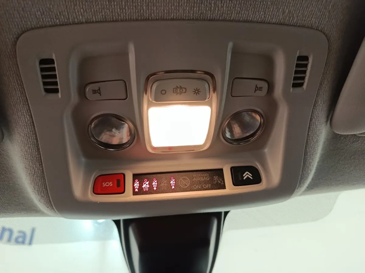 Vue en contre-plongée du plafonnier blanc de la Citroën C3 2020 avec éclairage et boutons SOS et airbag.