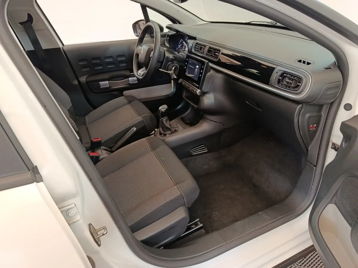 Vue intérieure côté conducteur de la Citroën C3 blanche 2020 avec tableau de bord noir et écran tactile central.