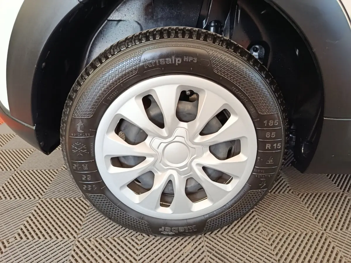 Gros plan sur la roue avant droite d'une Citroën C3 blanche, mettant en valeur la jante avec enjoliveur gris.